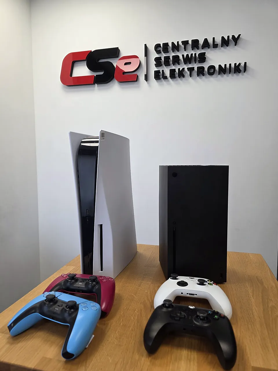 Xbox Series X i PlayStation 5 z padami na stole przyjęć w serwisie konsol CSE Poland
